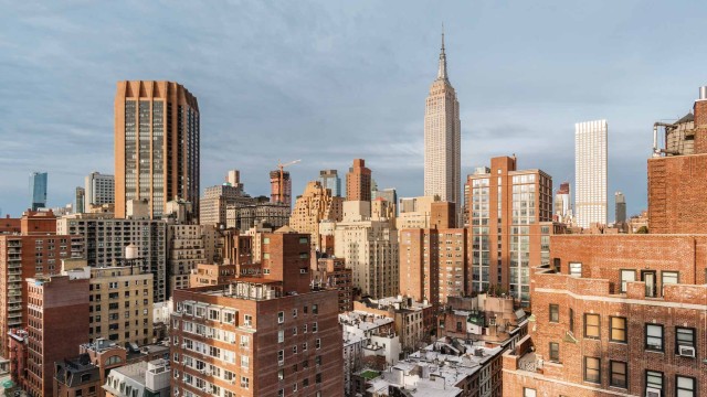 Die Skyline von New York City, eng aneinander gebauten Häusern, mit dem Empire State Building im Hintergrund. 